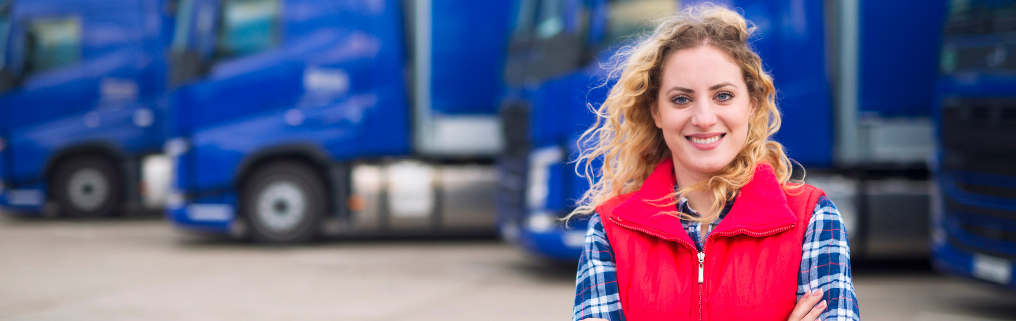 Woman stands in front of row of parked trucks.