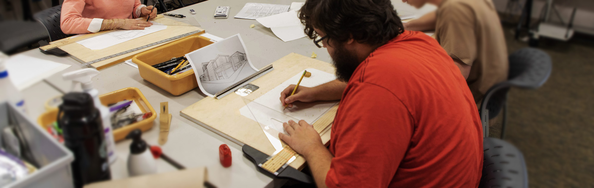 Students use triangles and mechanical pencils for architectural drawing.